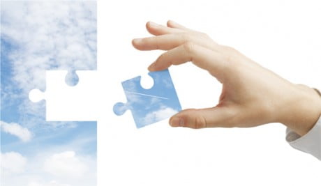 person putting the last puzzle piece together on a puzzle made of sky and clouds