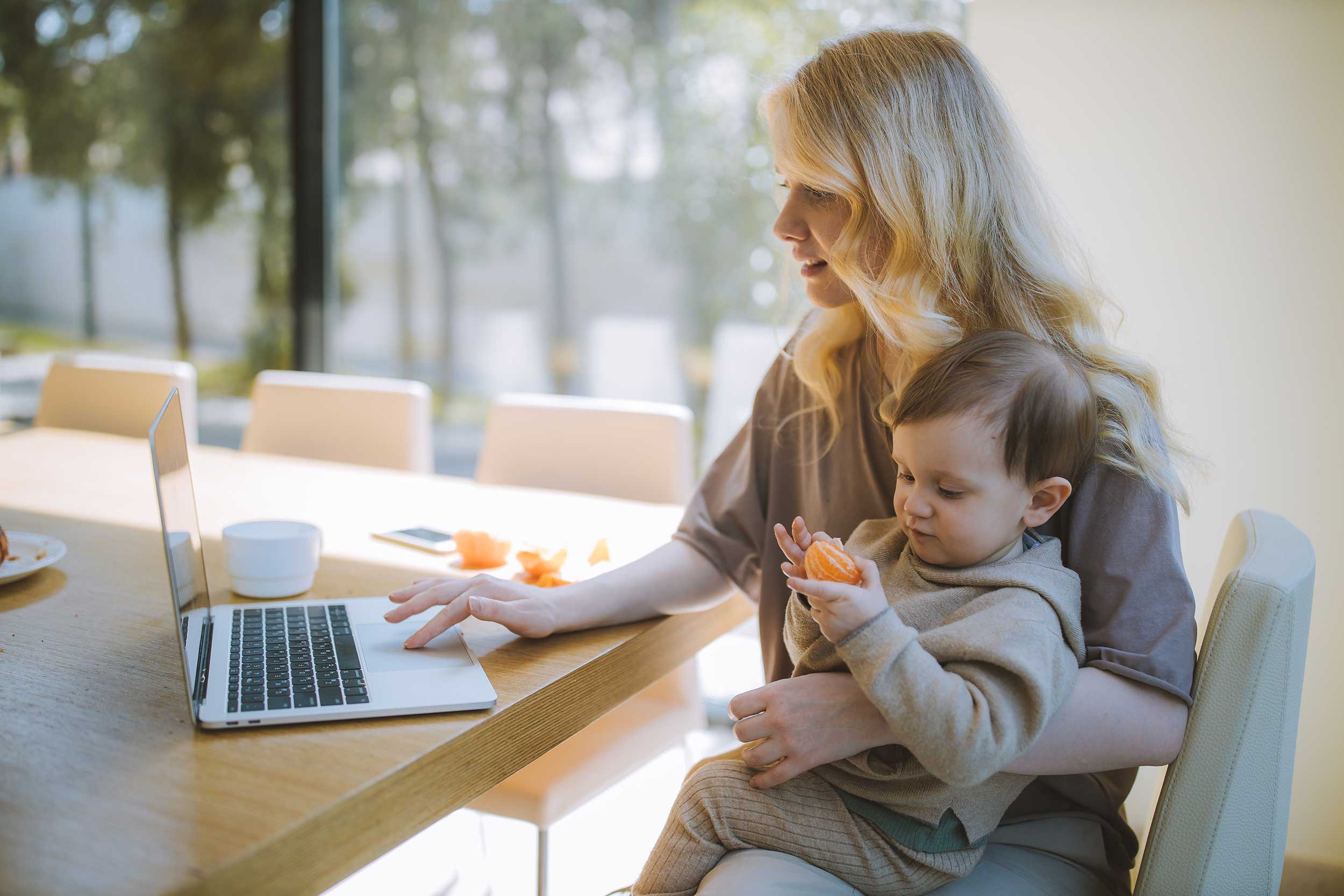 woman working from home with her young son in her lap