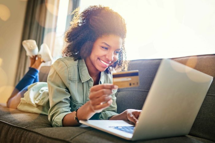 smiling women holding credit card looking at her laptop