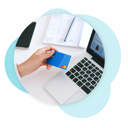 woman holding credit card next to laptop