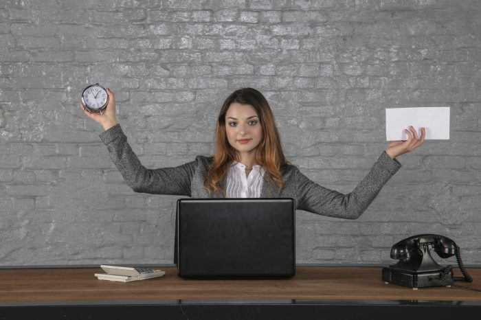A young businesswoman holds an envelope and a watch in her hands