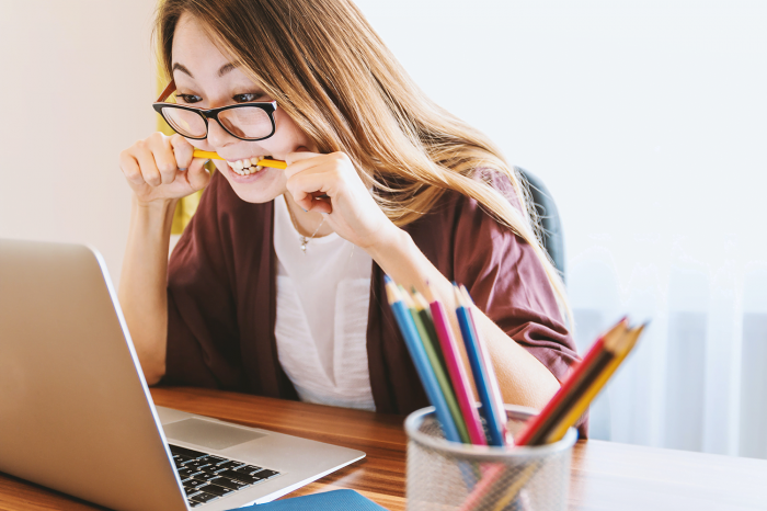 frustrated-woman-chewing-a-pencil-in-front-of-her-laptop