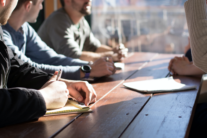 man-taking-notes-on-a-wood-table