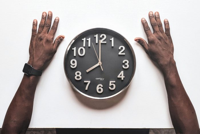 mans-arms-stretched-out-on-a-table-with-a-clock-in-front-of-him