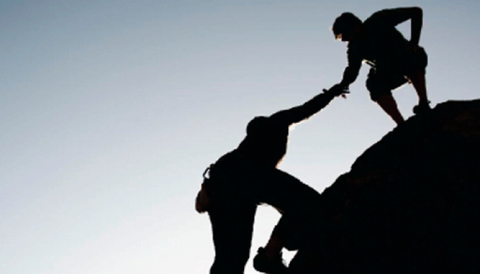person helping another person up a mountain